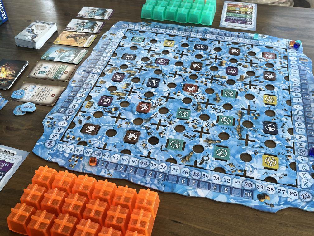 Ein Beispiel eines Aufbaus von Nunatak für drei Spieler. Man sieht die Spielsteine der Spieler, das Spielfeld sowie die Karten, die man im Spiel nehmen kann.